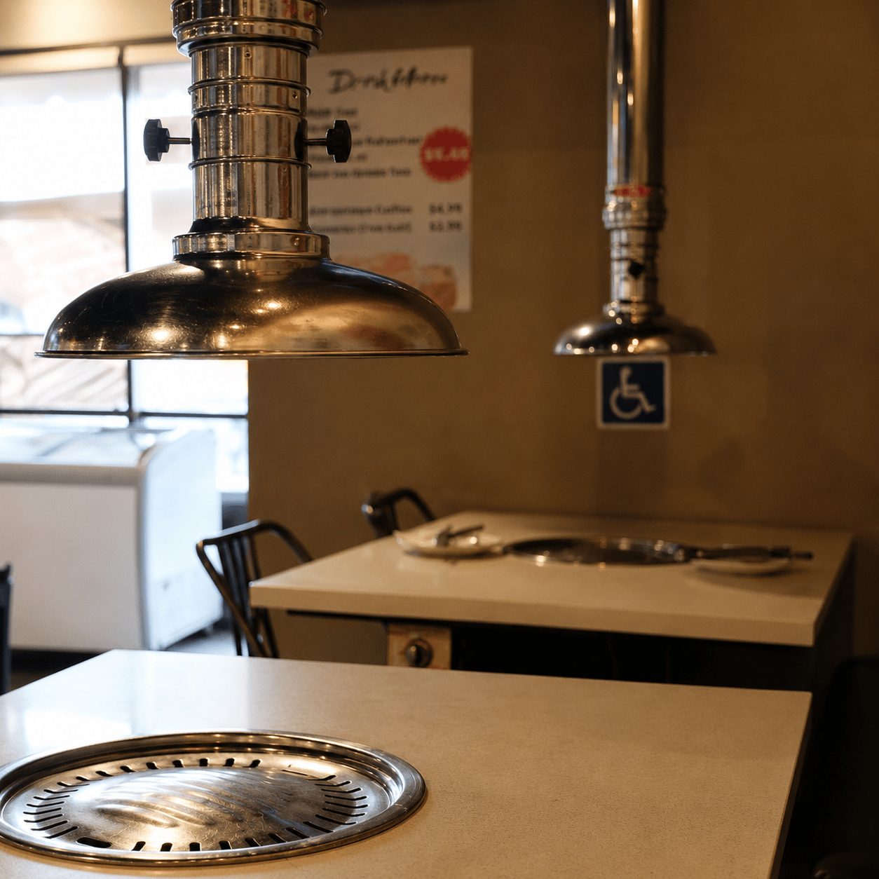 Chrome extraction hoods over a table with a built-in charcoal grill